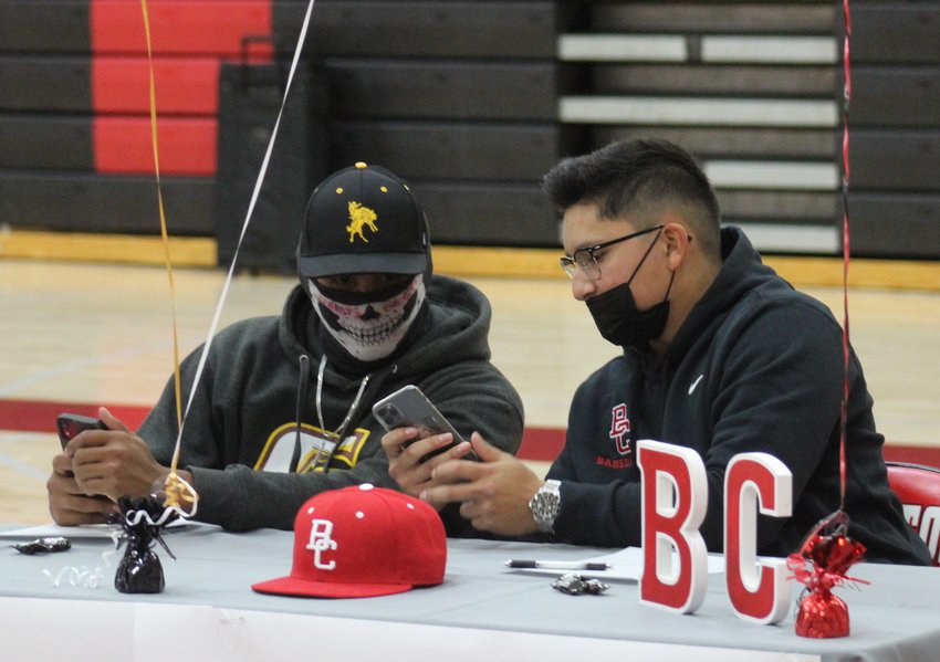 Levi Tucker, left, and Alek Martinez check their cell phones ahead of an April 26 letter-of-intent signing program at Brighton high School. Both are signing to play baseball. Tucker is heading to Garden City Community College, while Martinez is heading for Bakersfield Community College in California.